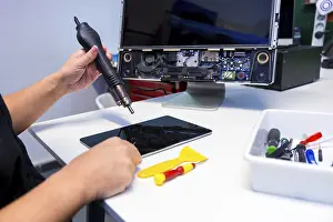 Quality Inspection Process Prints: Side view of an unrecognizable technician fixing a computer component using a soldering iron in a workshop