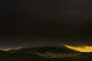 Cloudy Mountainous Terrain Prints: Volcano cone in dark cloud cover with dramatic lighting