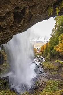 European Forest Landscapes Prints: A waterfall flows through a forest with a view of a distant building