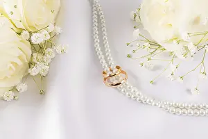 Traditional Wedding Ceremony Prints: Wedding rings placed gracefully on a string of pearls