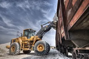 Deserted Building Site Prints: Wheel loader excavator with backhoe unloading clay