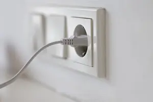 Power Supply Concept Prints: White power plug in a socket on the wall