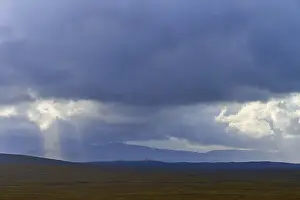 Atmospheric Landscape Photo Prints: Wide landscape with mountains under dramatic sky and rays of light breaking through clouds