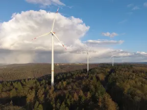 Wind Turbines In Forest Prints: Wind turbines perch over a thick forest with dramatic clouds in the sky