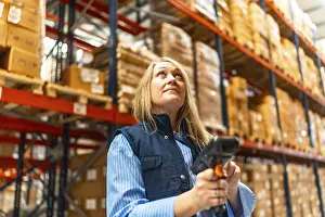 Inventory Management System Prints: Woman worker scanning package with bar code reader in a distribution warehouse