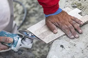 One Person Construction Team Prints: Worker grinding corner tile for fitting