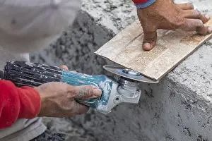 Construction Worker Tools Prints: Worker grinding corner tile for fitting