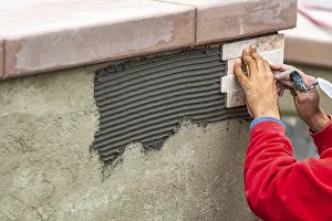 Masonry Work Prints: Worker installing wall tile at construction site