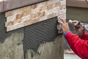 Manpower For Building Sites Prints: Worker installing wall tile at construction site