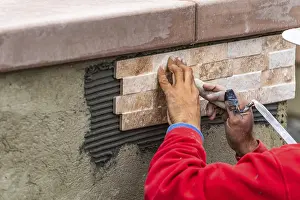 Masonry Craftsmanship Prints: Worker installing wall tile at construction site