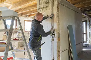 Empty Construction Area Prints: A worker installs cables on a construction site