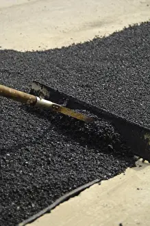 Road Construction Prints: A worker is smoothing fresh tar