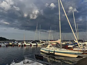 Prints of Yachts in harbor under dramatic cloudy skies, calm water and soft evening light create a peaceful atmosphere, Hjo, Lake Vattern, Sweden Yachts in harbor under dramatic cloudy skies Lake Prints: Yachts in harbor Print, Hjo, Lake Vattern, Sweden
