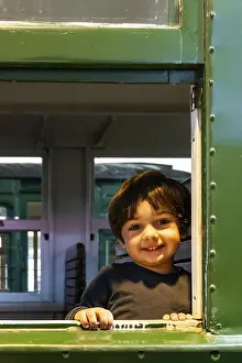 Young Boy Smiling Prints: A young boy is smiling at the camera from a train window