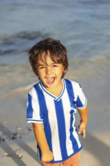 Blue Striped Shirt Prints: A young boy is standing on the beach