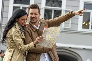 Prints of Young couple with city map and travel guide while visiting a city on holiday Austria Map Prints: Young Couple with City Map Print in Austria