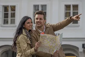 Prints of Young couple with city map and travel guide while visiting a city on holiday Austria Map Prints: Young Couple with City Map and Travel Guide Print, Austria