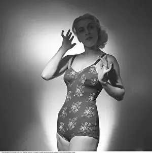 Retro Swimwear Designs Prints: A young female model poses confidently in a photo studio wearing a period-typical one-piece swimsuit in 1946