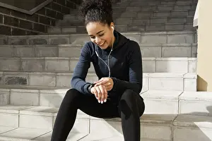 Sportsman Training Routine Prints: Young female runner checking her pulse with an activity tracker after training