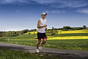 Athletic Young Adult Prints: A young man jogging through the fields