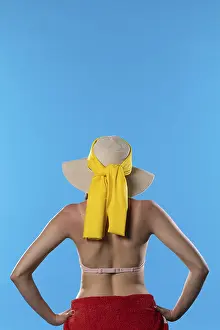 Woman In Swimsuit Prints: A young woman with a hat on her head and a tan on her back stands in full sun