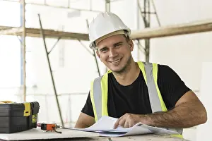 Construction Site Worker Prints: Young is worker checking blueprints during his work on a construction site